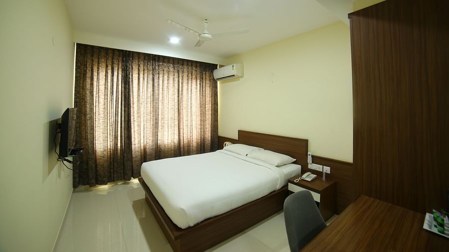 Mysore Gate Hotel, Bangalore Bengaluru A room consisting of a well made bed a TV a study desk and chair and an air conditioner - Mysore Gate Hotel Bangalore
