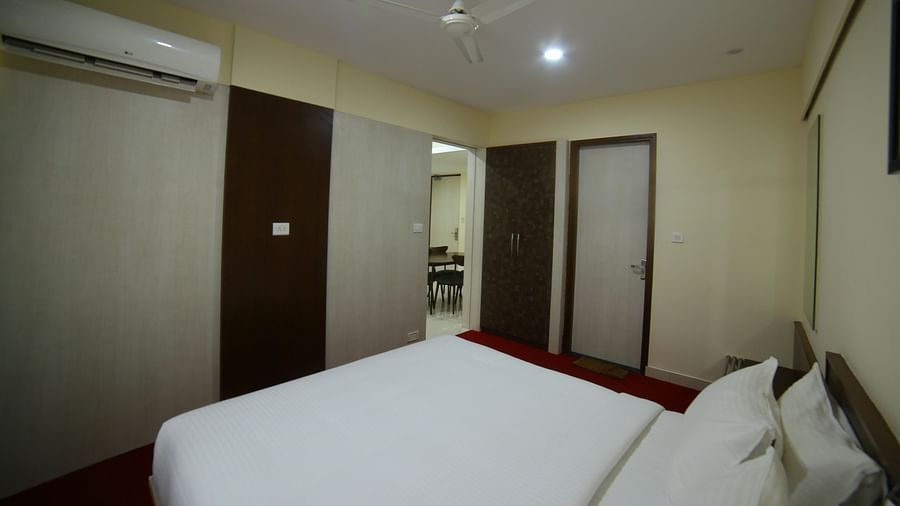 Mysore Gate Hotel, Bangalore Bengaluru A room with well made bed an air-conditioner and a door opening to a separate Living area