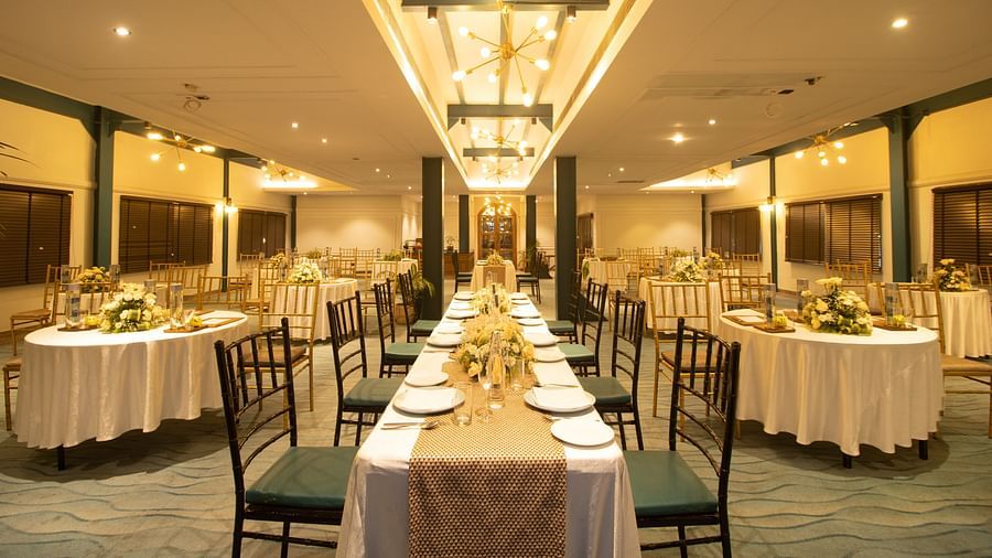 Indoor banquet hall with long dining tables set for an event, elegant centrepieces, and warm ambient lighting. - Polo Floatel, Kolkata