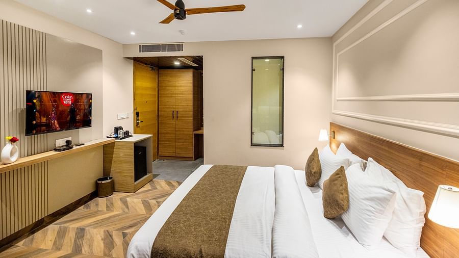 Superior Room at Pride Hotel Rishikesh featuring a plush bed in front of a TV mounted on the wall with coffee maker on the side table below it