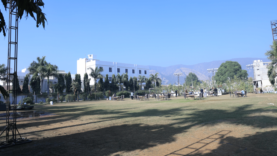 A wide outdoor space with a grass field, landscaping, and views of distant hills | Pride Premier Alwar