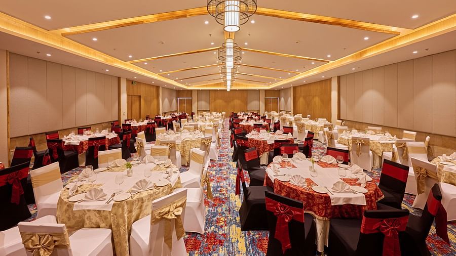 A Large event hall with round table style seating and elegant chandeliers - Royal Tulip, Chitwan