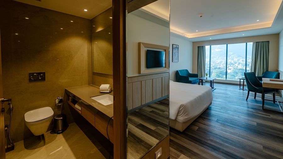 A hotel room with a stylish bathroom, elegant lighting, and a bedroom offering beautiful views - Sarovar Portico, Ajmer