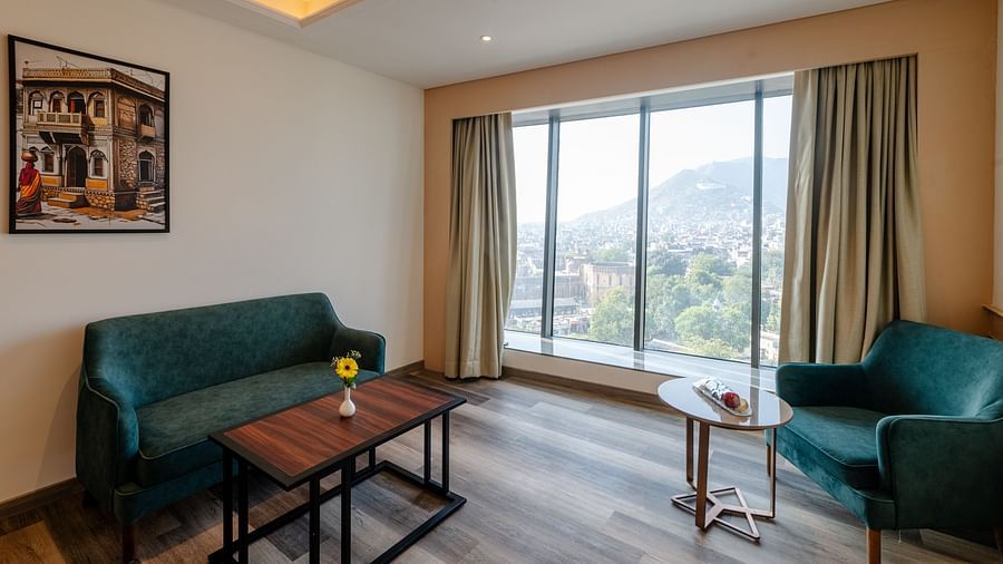 A lounge area with teal sofas, teapoys and large windows with scenic views - Sarovar Portico, Ajmer