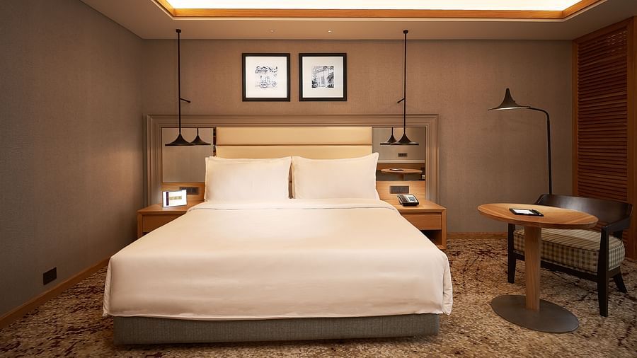 a room image with a bed, table, chair all arranged and  false ceiling lights giving a warm ambience