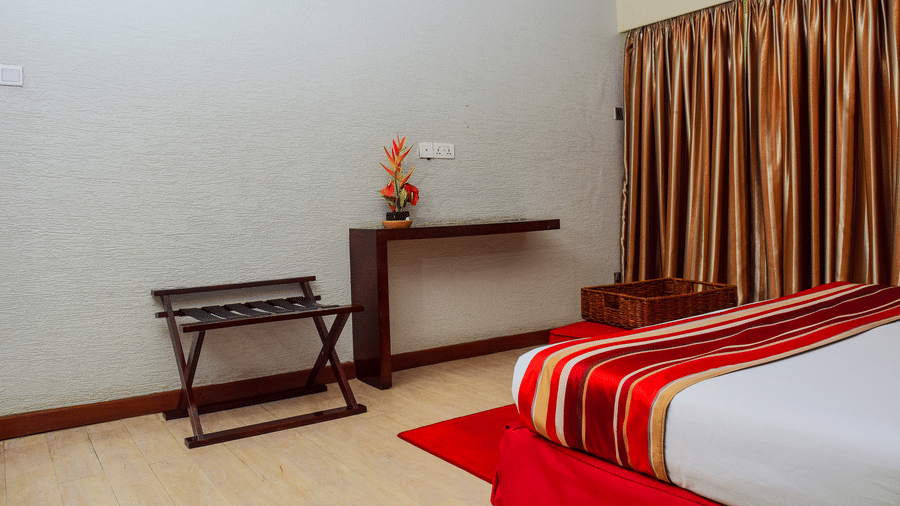 The bedroom of the Suite with bedside table and curtains at The Zehneria, Nairobi.