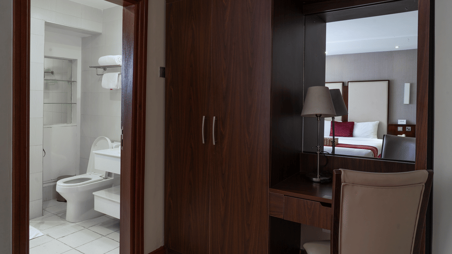 The attached washroom in a hotel room in Nairobi at The Zehneria. The wardrobe is seen beside the entrance to the washroom entrance.