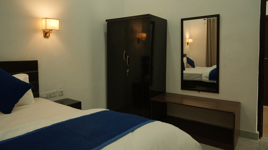 Room with a king size bed, wooden wardrobe, dressing mirror and work surface.