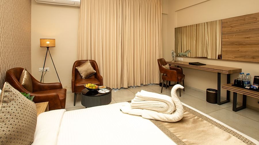 Side view of a hotel room featuring a bed, a wall-mounted TV, and chairs for seating