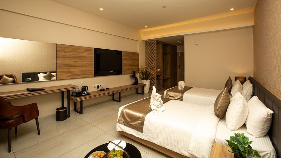 Hotel room with twin beds, a TV mounted on the wall, and ceiling interior lighting