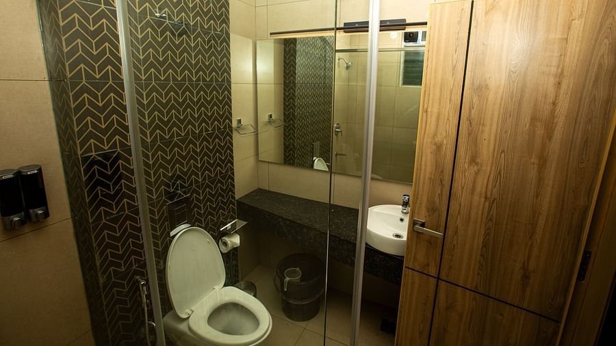 Hotel washroom with a mirror, sink, and a separate glass-enclosed space