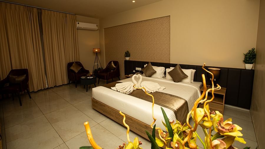 Spacious king-sized bed with a bedside lamp, two chairs, and a round table in the corner