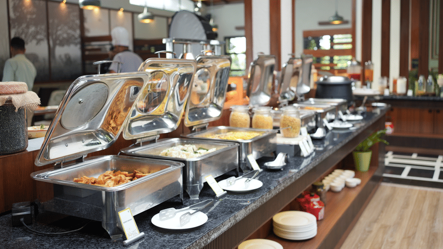 A restaurant buffet spread with multiple chafing dishes containing various food items at The Golden Tusk, Jim Corbett