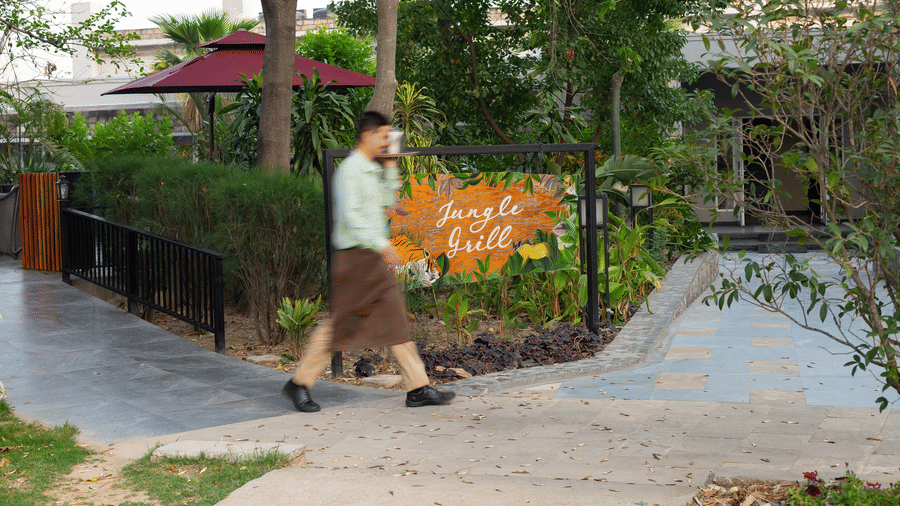 A person walking along a paved pathway in a landscaped garden area of a restaurant  at The Golden Tusk, Jim Corbett