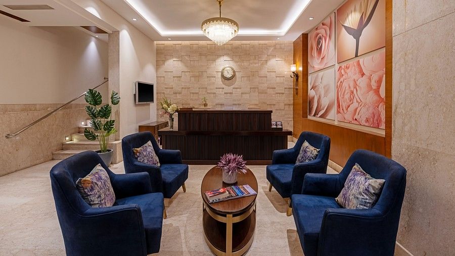 Lobby view with four blue  loveseats and a wooden center table at Hotel Saket 27, New Delhi