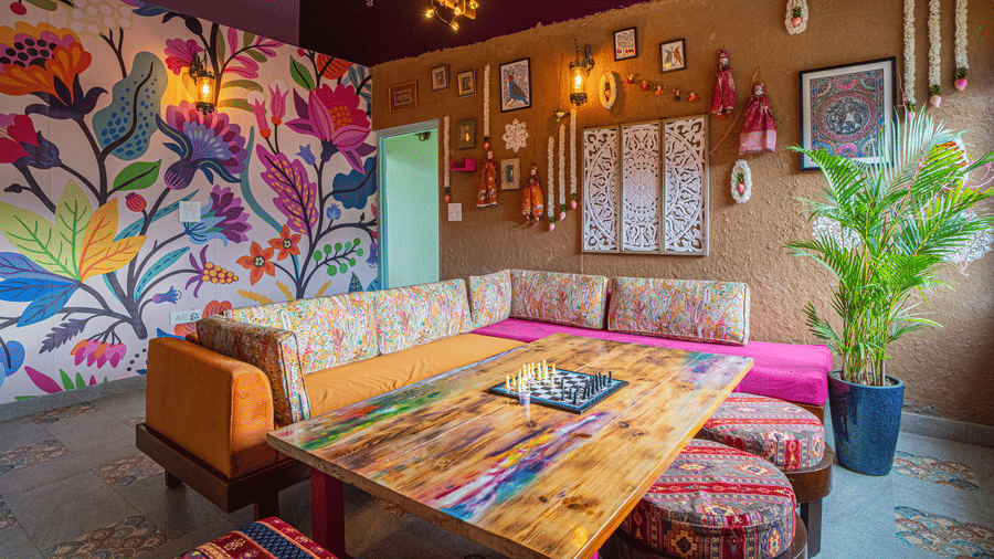 A lounge with a 2 sofas, wall paintings, chairs, and decor items arranged indoors at Adrushya Estates, Mukteshwar.