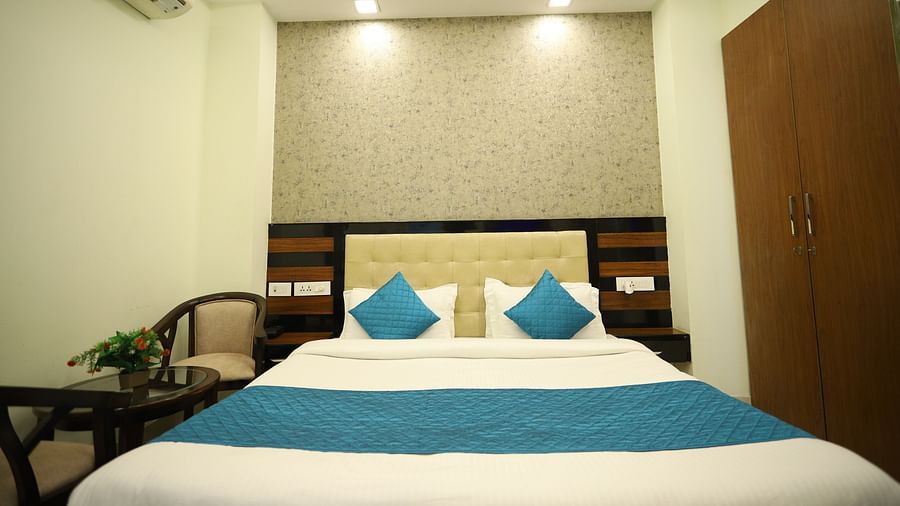 A room with a double bed featuring blue and white bedding, bedside tables, and a patterned headboard - Asian Suites Cyber Park, Gurgaon