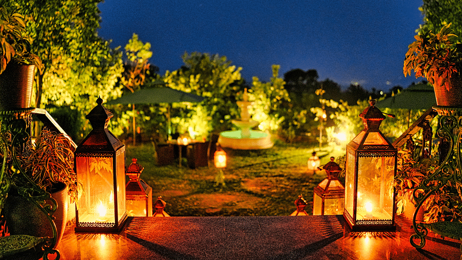 Outdoor dining area with lanterns and string lights lit in the evening - Atman, Dharamshala