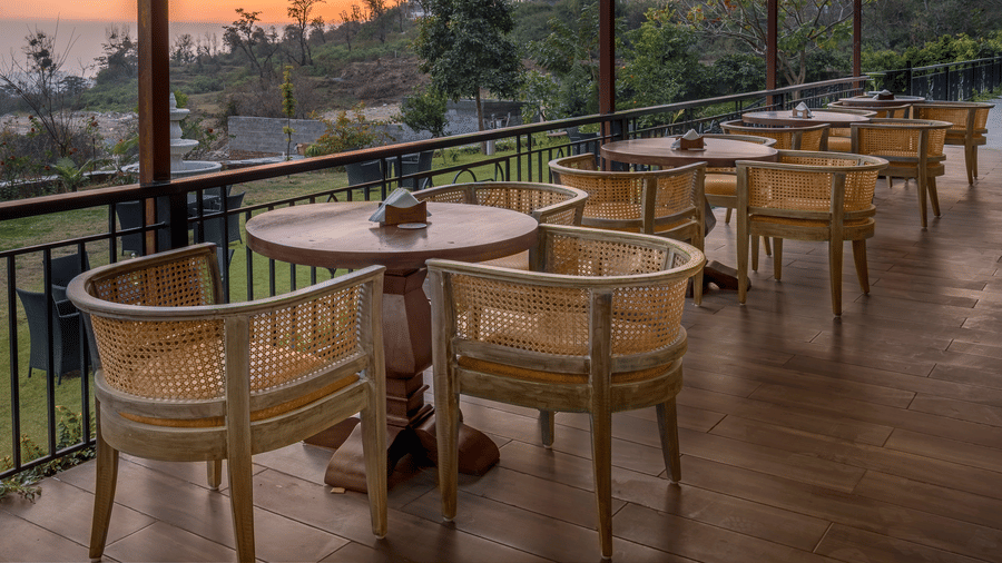 The Fuzion cafe located on a deck with views of the forest and clusters of tables and chairs in a line - Atman, Dharamshala