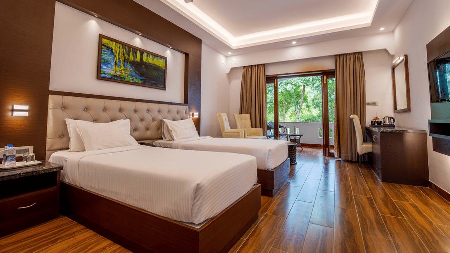 Premium Twin Room at Avana Resort featuring 2 twin beds, an accent wall, wooden floors, and a ceiling fan.