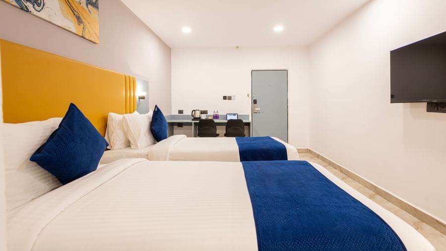 Close up side view of Superior Room featuring a bed with blue and white bedding, a yellow headboard, and modern furnishings including a desk and TV - Beestay Hotel Financial District, Hyderabad