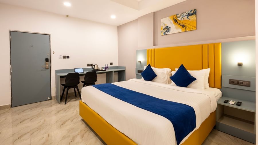 Overview of a modern Premium Room with a bed featuring blue accents, a work desk area, and a door on the left  - Beestay Hotels Financial District, Hyderabad 