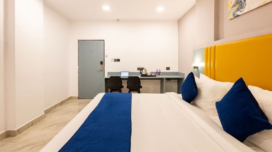 A modern Premium Room with a bed featuring blue accents, a work desk area, and a door on the left  - Beestay Hotels Financial District, Hyderabad 