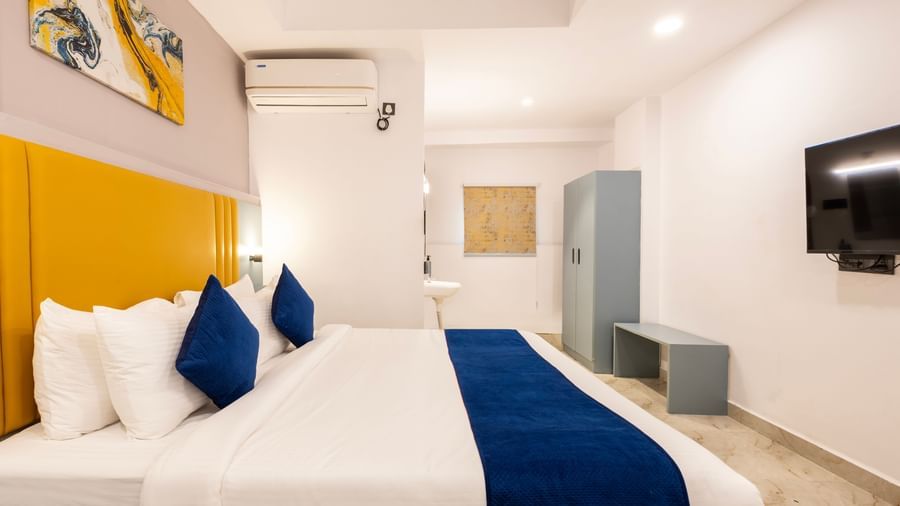 Side view of a modern Premium Room with a bed featuring blue accents, a work desk area, and a door on the left  - Beestay Hotels Financial District, Hyderabad 