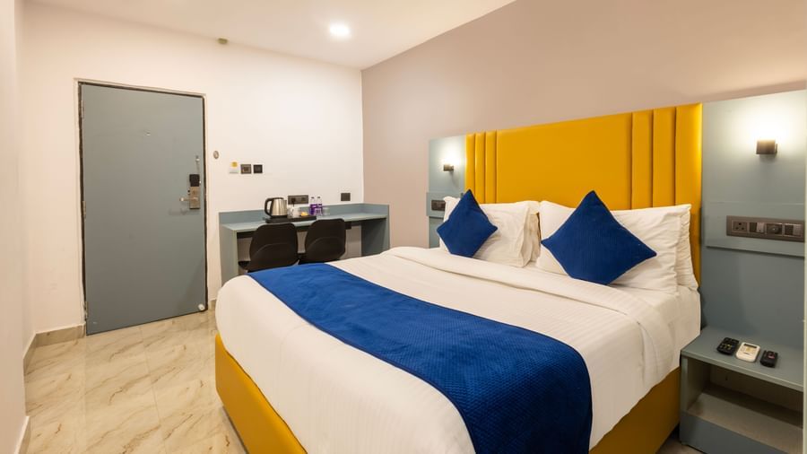 A Deluxe Room with a bed, blue and white bedding, a yellow headboard, and a desk area - Beestay Hotels Financial District, Hyderabad 