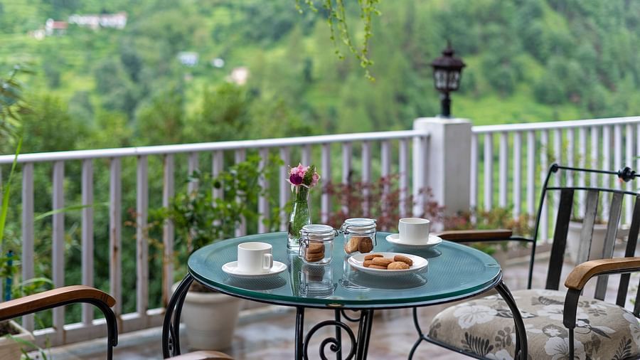 Scenic outdoor tea setup with pastries overlooking lush green hills at BluSalzz Collection - Suvaasa Resort, Ramgarh.