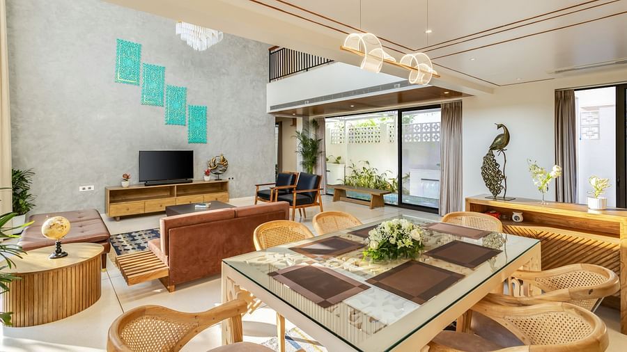 A bright and modern dining area with a large wooden table, contemporary chairs, and an open-plan kitchen in the background - BluSalzz Villas - Alocassia, Anjuna