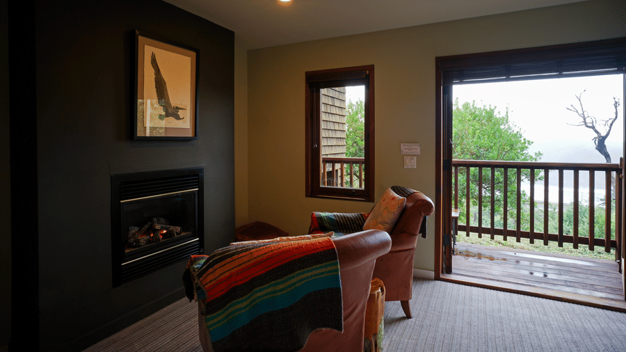 Interior view of a room with a fireplace, seating, and an open doorway leading to a balcony - Brewery Gulch Inn & Spa