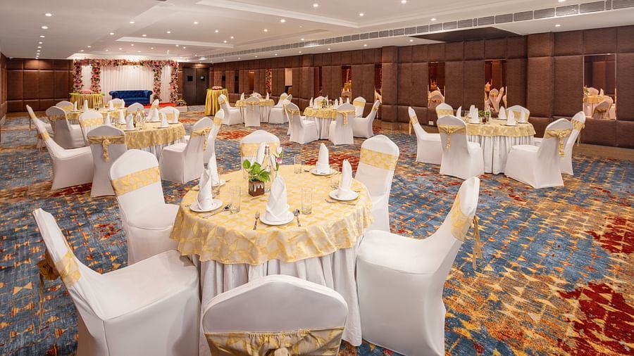 An image of a banquet hall with several chairs and table sets spread out - Brij Eternity, Vrindavan