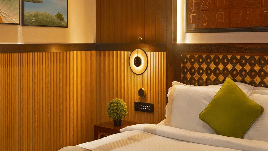 Image of Coral Teal Suite at Coral Reef Resort and Spa in Havelock featuring a plush bed placed against a patterned wall lit up with warm lights and a lamp mounted on the wall next to it over the nightstand