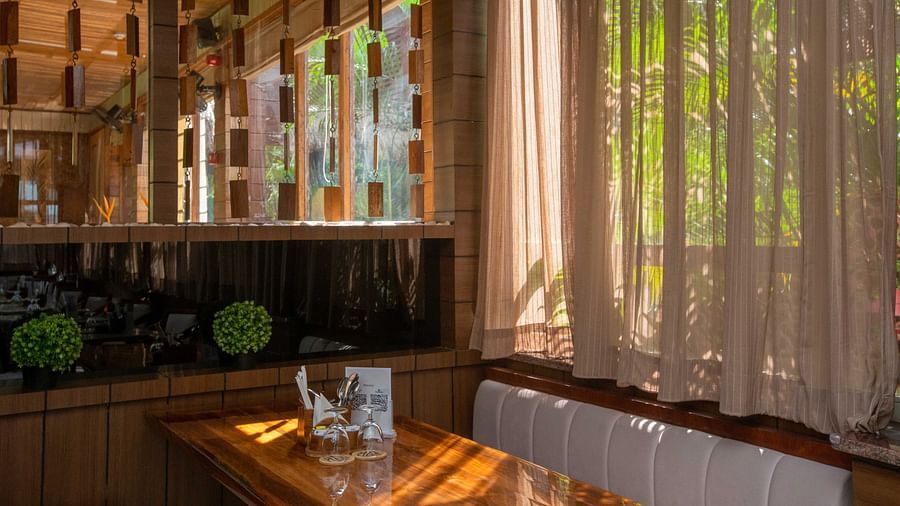 5th Bistro Cafe and Bar at Coral Reef Resort & Spa, Havelock featuring a stylish and modern area with sheer curtains letting in natural light. The space is lush with tropical plants, creating a relaxed yet sophisticated vibe - Coral Reef Resort & Spa, Have