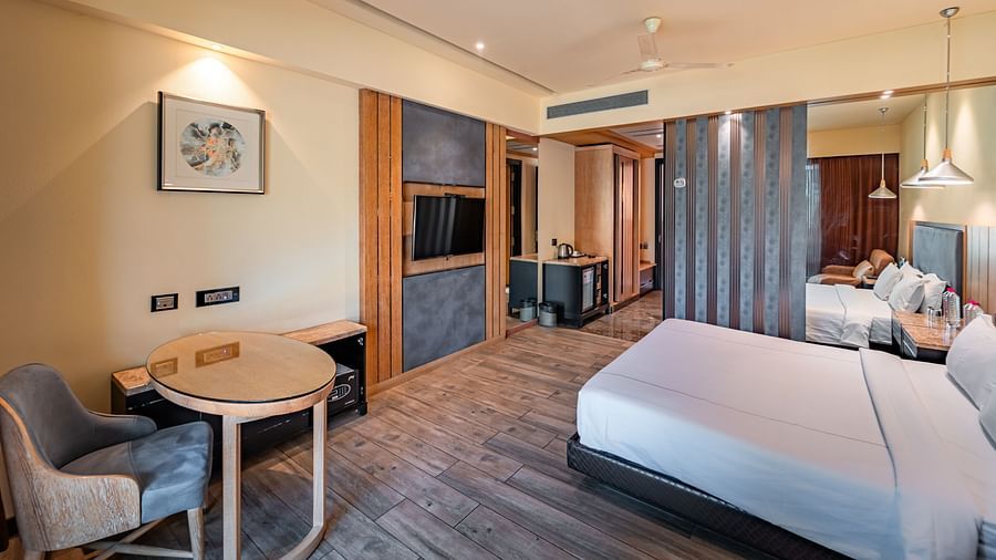 Club Room features a spacious bed, a round study table with a chair, a wall-mounted television, and an air conditioner fixed to the side at Crescent Spa & Resort, Indore