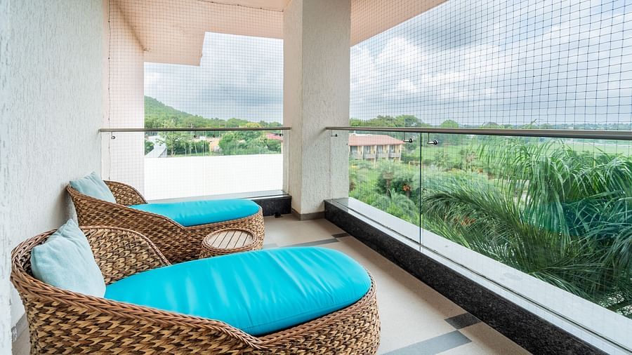 Two oval cushioned chairs are positioned on the balcony for enjoying the view at Crescent Spa & Resort, Indore