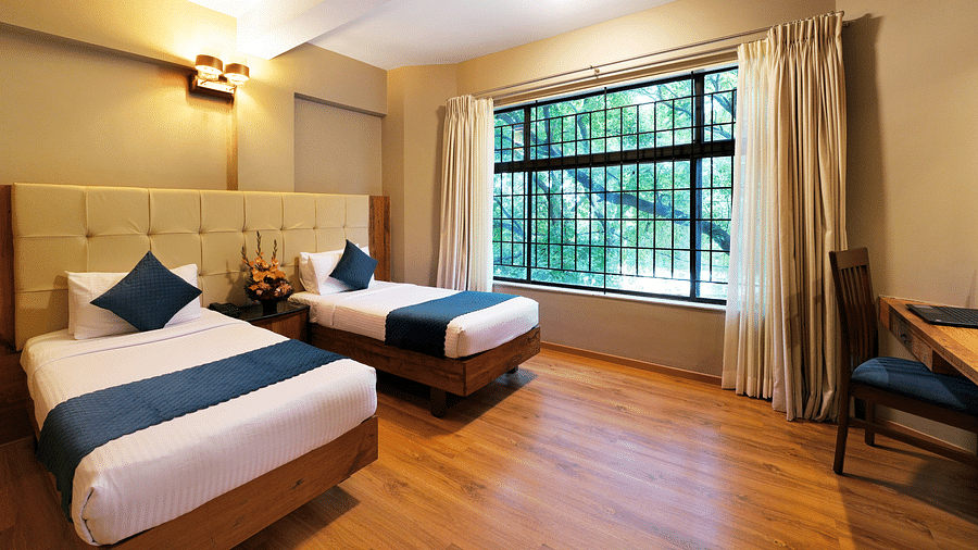 An image of our Deluxe Room featuring twin beds and a view from the window - Cross Roads Inn, Bengaluru