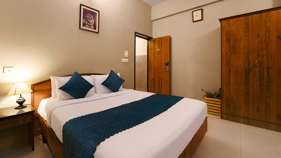A Deluxe Room with a queen size bed, minimalist design, and modern amenities - Cross Roads Inn, Bengaluru
