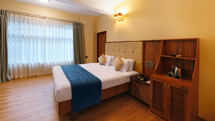 A room in bengaluru with large windows, a queen size bed, and wooden decor - Cross Roads Inn, Bengaluru