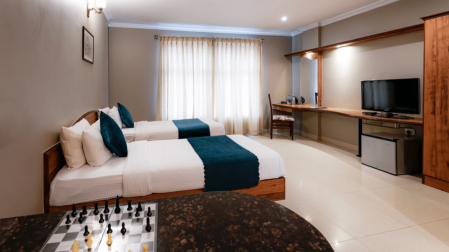 An Executive Room with twin beds, a desk with a chessboard, and stylish decor - Cross Roads Inn, Bengaluru