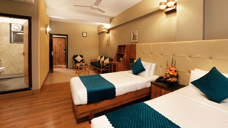  An Executive Room with cosy twin beds, a couch, and a glass-partitioned bathroom - Cross Roads Inn, Bengaluru