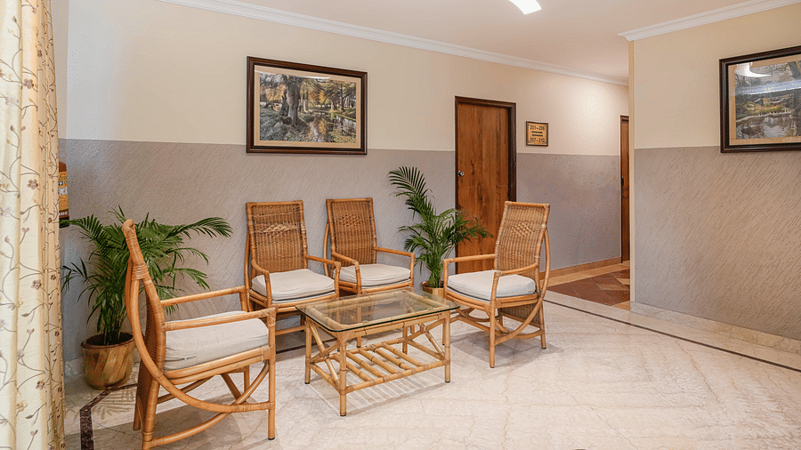 An image of a lobby with seating arrangement, potted plants, warm lighting, and modern decor - Cross Roads Inn, Bengaluru