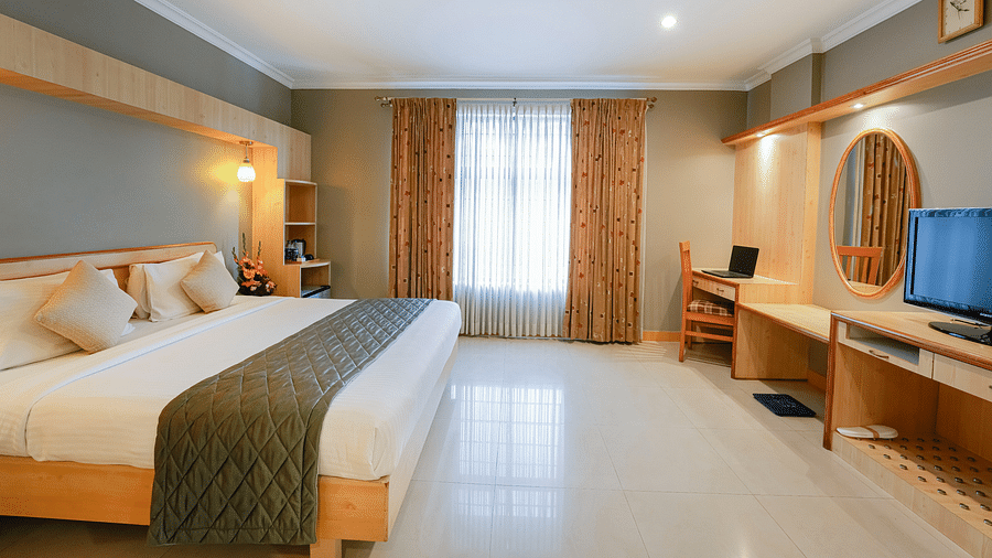 An image of a Suite with plush bedding, a work desk, and ample natural light - Cross Roads Inn, Bengaluru