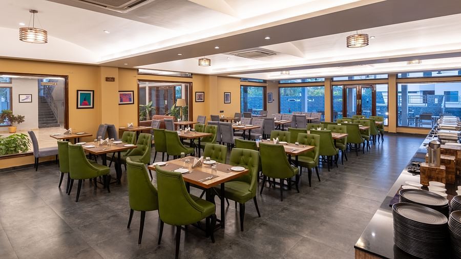 Diagonal view of the restaurant at DLS Forest Vines Resort, featuring tables and seating set for guests.