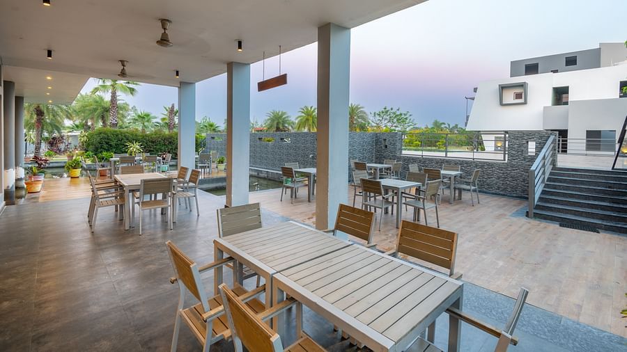 Outdoor dining area at DLS Forest Vines Resort with wooden tables and chairs.