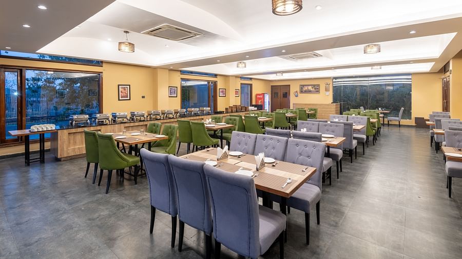 Diagonal view of the restaurant at DLS Forest Vines Resort, featuring tables and seating set for guests.