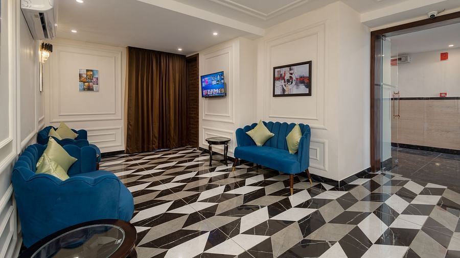 Image of the seating area at the reception of DLS Grand Luxotica, Dehradun featuring sofa sets and side tables placed right beneath the air conditioner