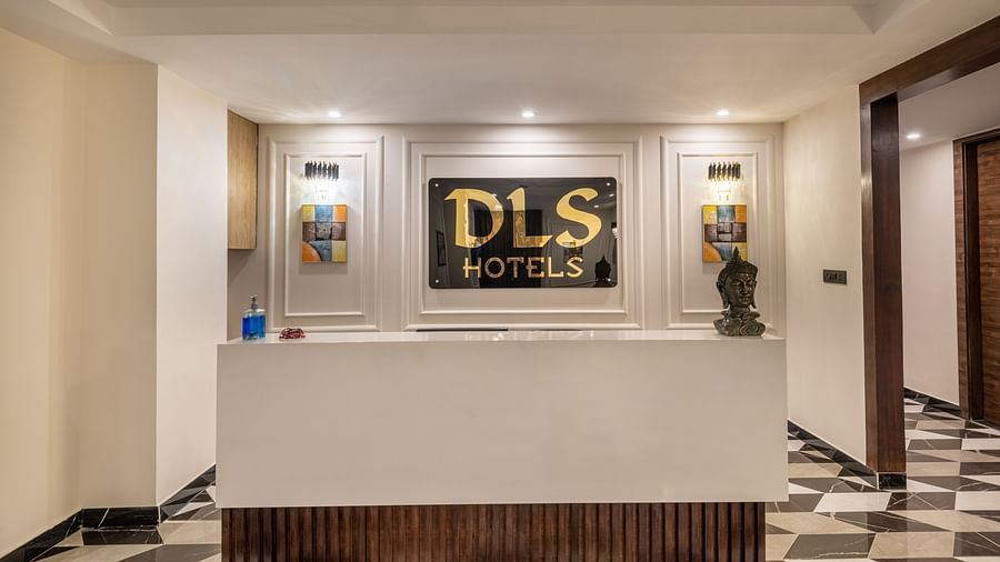 Image of the reception desk at DLS Grand Luxotica, Dehradun in warm lighting with a signage of DLS Hotels written on the wall behind the desk