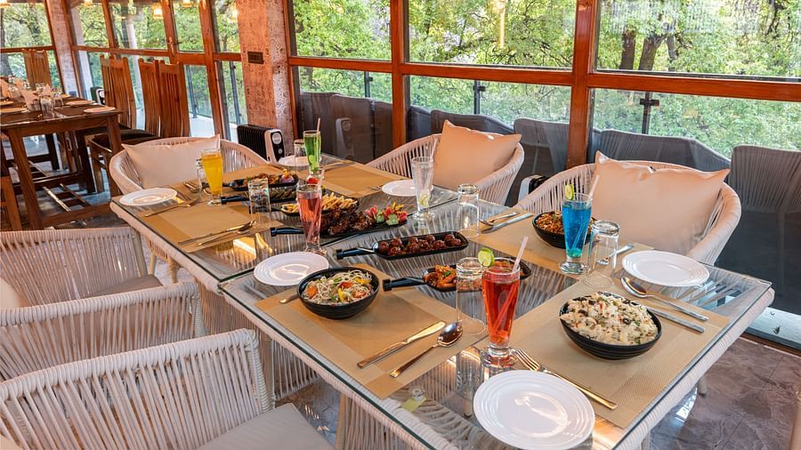 An image of the restaurant chairs and tables with food platters laid on it - DLS The Emerald, Nainital